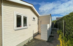 Ein eingeschossiges Haus mit Eingangstür, kleinem Fenster und einem sichtbaren Außenbereich mit einem gepflasterten Weg.