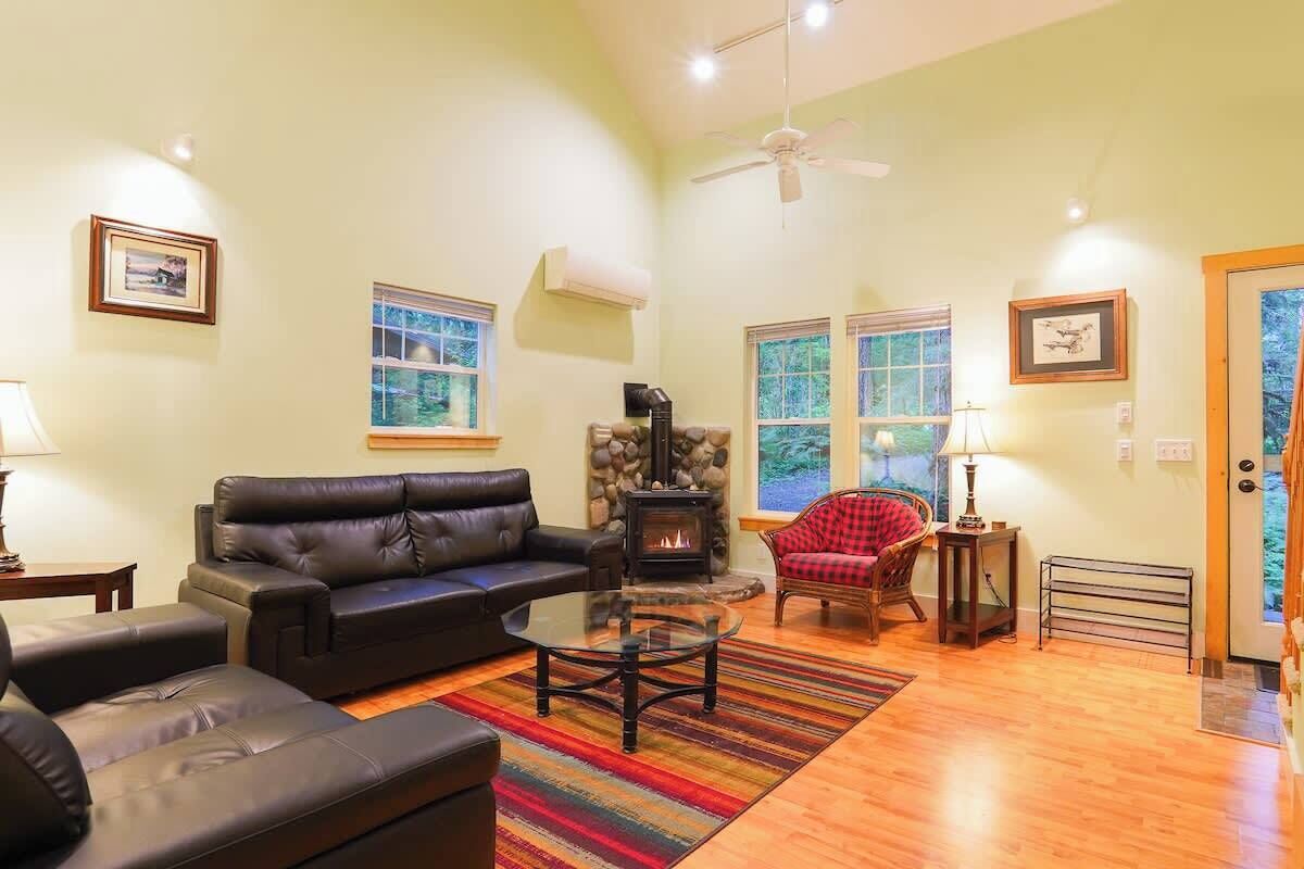 Una sala de estar con chimenea, sofá de cuero y una silla roja.