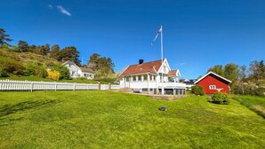 En vit byggnad med en röd ladugård, omgiven av ett vitt trästaket och grön gräsmatta.