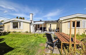 A two-story house with a patio, a wooden table, and a chair. - Beautiful home in Tolvsrød (Tolvsrød)
