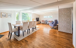 A spacious room with a dining area, a seating area with a TV, and a large window with a view of greenery. - Beautiful home in Tolvsrød (Tolvsrød)