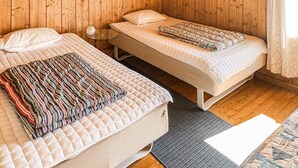Een kamer met twee bedden, een klein tafeltje en een kamerjas met een patroon.