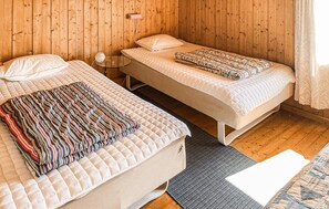 Ein Zimmer mit zwei Betten, einem kleinen Tisch und einer gemusterten Decke.