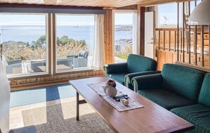 Ein Zimmer mit Meerblick, einem grünen Sofa, einem Holztisch und einem Fenster mit Vorhängen.