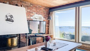 Een keuken met een bakstenen muur, een groot raam met uitzicht op zee, een tafel met een bloevas en een tv op een meubel.