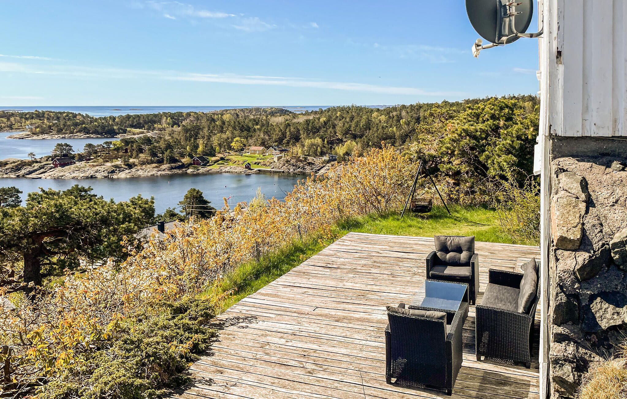 A wooden deck with outdoor furniture overlooking a lake and forested area.