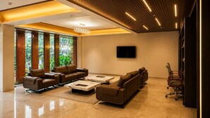 A modern living room with leather sofas, a flat-screen TV, and a large window with a view of greenery.