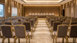 A conference room with rows of chairs, a stage, and a curtain backdrop.