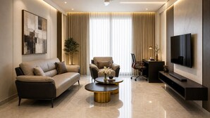 A modern living room with a sofa, armchair, coffee table, TV, and a ceiling fan.