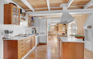 Eine moderne Küche mit Holzschränken, einer zentralen Kochinsel und einem Essbereich mit Stühlen.