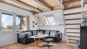 Un appartement moderne de style « loft », doté d’un lit en mezzanine, d’un coin repas et d’une grande fenêtre.