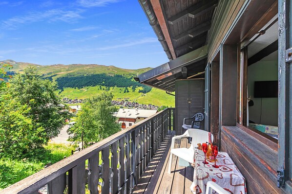 Un balcon avec une table, des chaises et une vue panoramique sur une vallée.