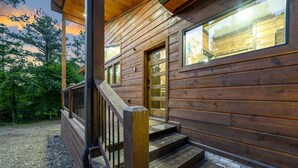 Une cabane en bois avec une véranda, des marches et une fenêtre.