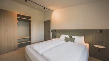Une chambre moderne avec un grand lit, une armoire intégrée, des tables de chevet et une petite table ronde.