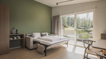 A modern bedroom with a bed, a desk, and a view of a green landscape through the window.