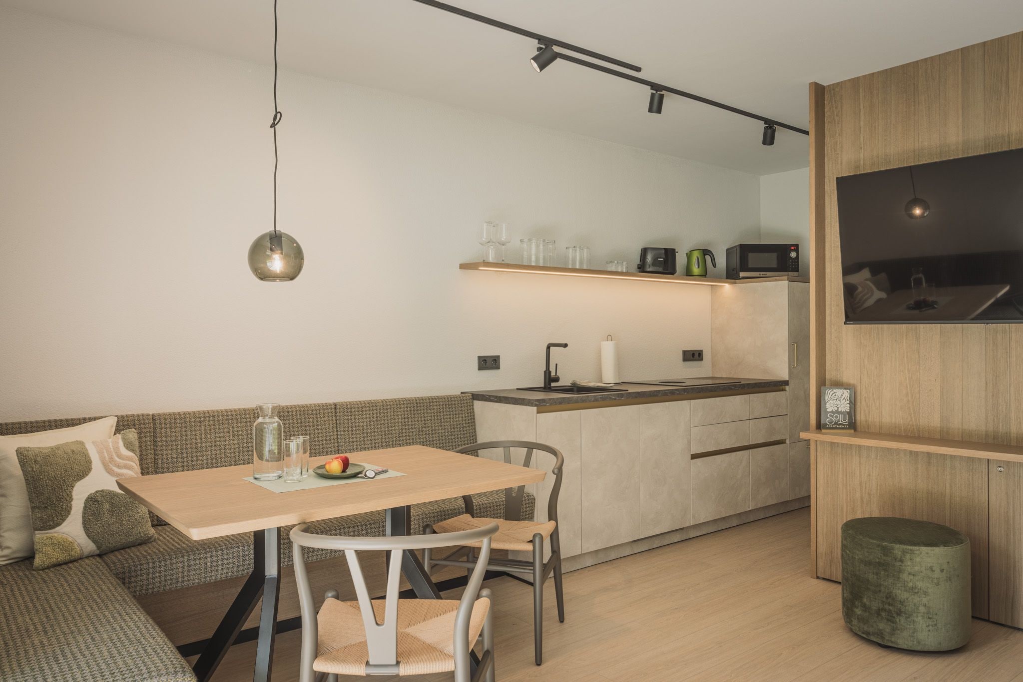 Une cuisine moderne dotée d’un îlot central, d’un coin repas avec une table et des chaises, et d’un banc intégré.