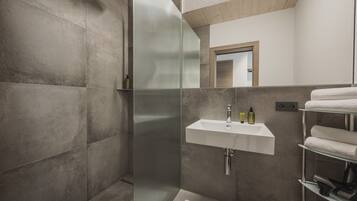 Un baño moderno con cabina de ducha de vidrio, un lavabo blanco y un perchero para toallas.