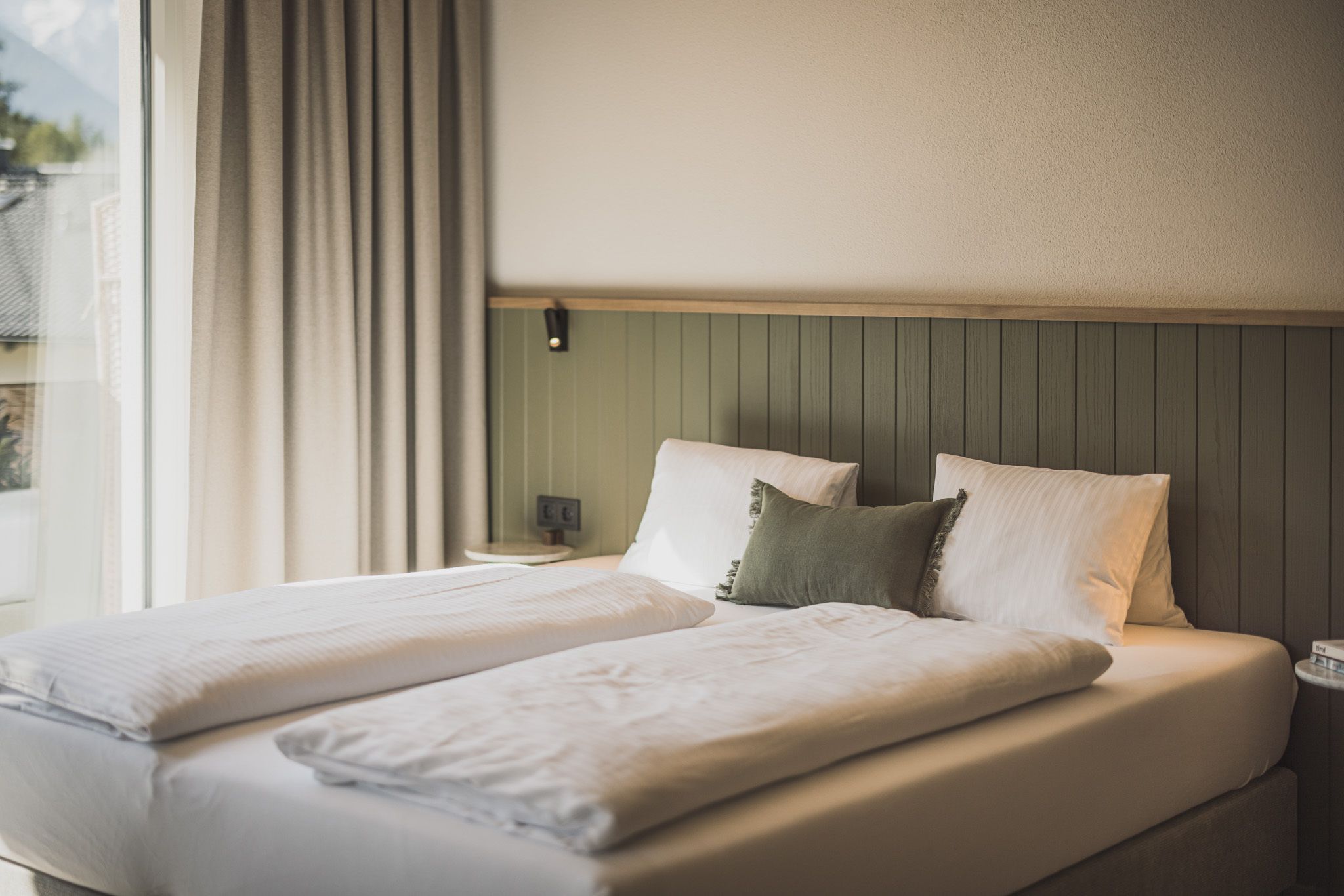 A double bed with two pillows, a bedside table, and a wall-mounted light fixture.