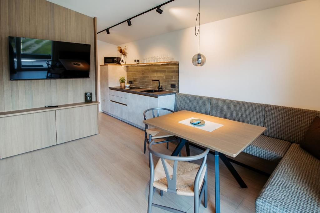 A modern kitchen with a built-in TV, a dining area with a table and chairs, and a seating area with a sofa.