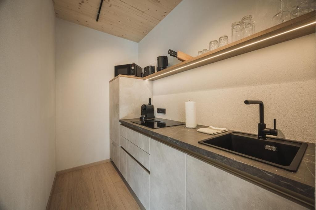 A compact kitchen with a built-in sink, a microwave, and a coffee maker on the countertop.