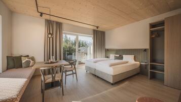 Ein modernes Hotelzimmer mit Holzboden, einem großen Bett, einem Schreibtisch mit Stuhl und Blick ins Freie.