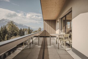 Un balcón con vistas a las montañas, techo de madera y una mesa con sillas.