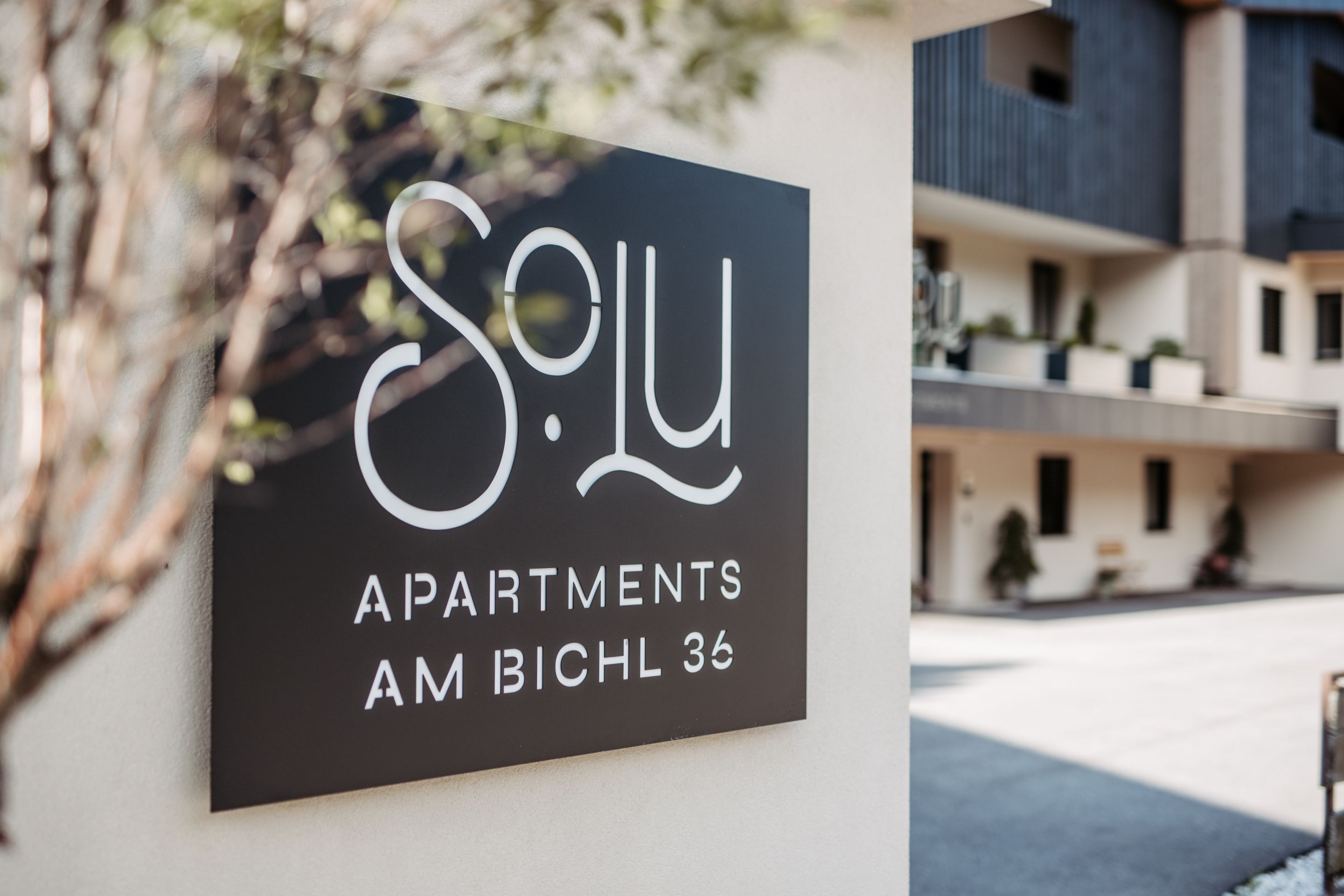 A sign for 'S. L. Apartments' with a modern architectural style.