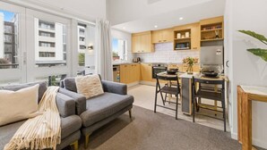 En modern lägenhet med en grå soffa, ett litet kök och en matplats.