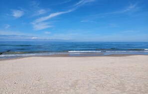Ein Strand mit blauem Himmel und ruhigem Meer.