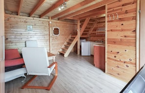 Ein Holzhaus-Interieur mit Essbereich, einer Couch, einer Treppe und einer Küchenzeile.