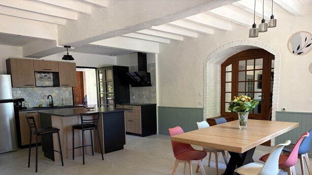 A modern kitchen with a central island, dining area with colorful chairs, and a large arched doorway. - Villa Les Tilleuls - Gîte 6 people Graçay Berry | Telecommuting & Family" - Telecommuting & Family (GRACAY)