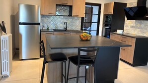 A modern kitchen with a central island, stainless steel appliances, and a patterned backsplash. - Villa Les Tilleuls - Gîte 6 people Graçay Berry | Telecommuting & Family" - Telecommuting & Family (GRACAY)
