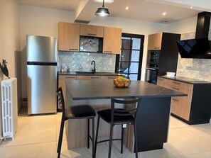 A modern kitchen with a central island, stainless steel appliances, and a patterned backsplash. - Villa Les Tilleuls - Gîte 6 people Graçay Berry | Telecommuting & Family" - Telecommuting & Family (GRACAY)
