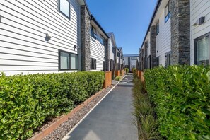 Eine Wohnstraße mit modernen Häusern, einem Betonweg und ordentlich geschnittenen Hecken.