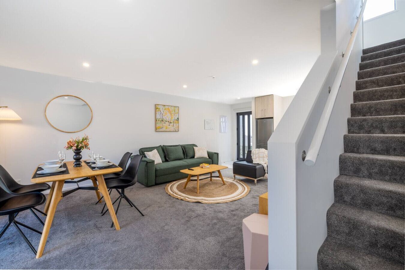 Un salon moderne comprenant un coin repas, un escalier et une vue sur l’extérieur.