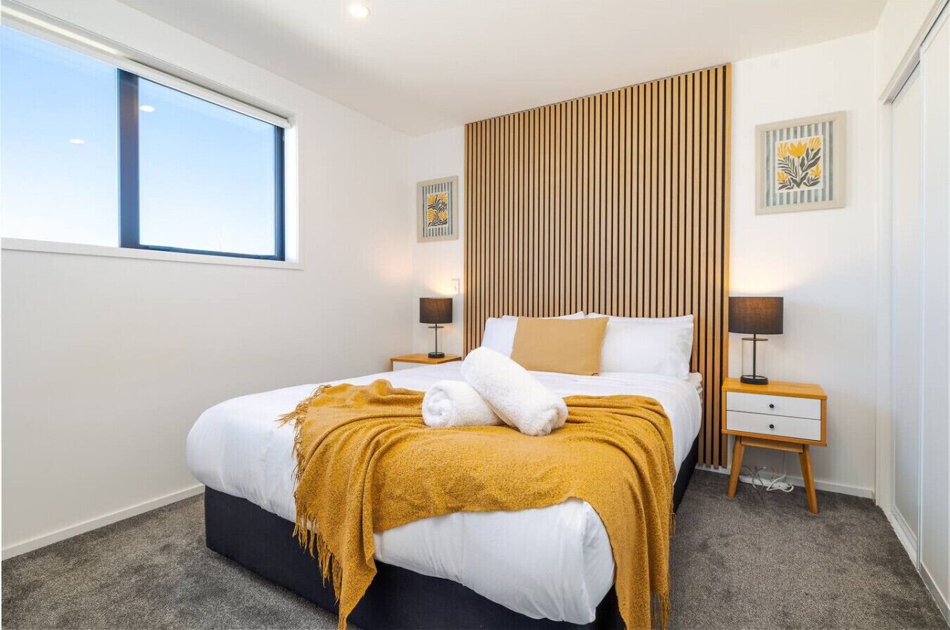 Habitación de hotel con cama, mesita de noche, ventana y una obra de arte colgada en la pared.