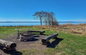 En picknickplats vid sjön med en eldstad, bänkar och utsikt över vattnet.