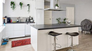 Une cuisine moderne avec des meubles blancs, un plan de travail noir et deux tabourets de bar.