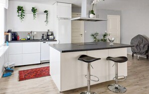 Ett modernt kök med vita skåp, en svart bänkskiva och två barstolar.
