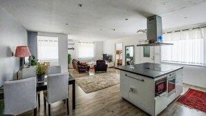 Une cuisine moderne avec un îlot central, un coin repas avec des chaises, un canapé et un tapis.