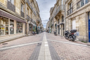 Une rue étroite, bordée de bâtiments des deux côtés, un ciel dégagé et quelques motos garées.