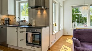 Eine moderne Küche mit Kochinsel, eingebautem Ofen und Blick auf Grünflächen.