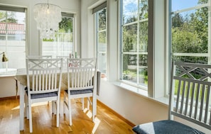 A dining area with white chairs, a table, and large windows with a view of greenery. - Stunning home in Gotlands Tofta (Gotlands Tofta)