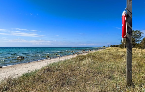 A beach with a wooden post and a red buoy, clear blue sky, and calm sea. - Stunning home in Gotlands Tofta (Gotlands Tofta)