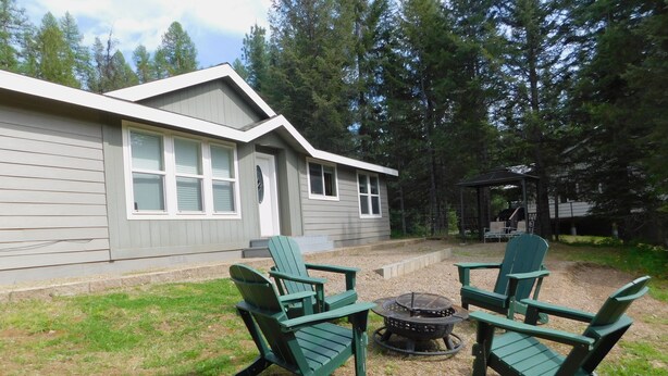 Une cabane avec un foyer et des fauteuils Adirondack dans la cour.