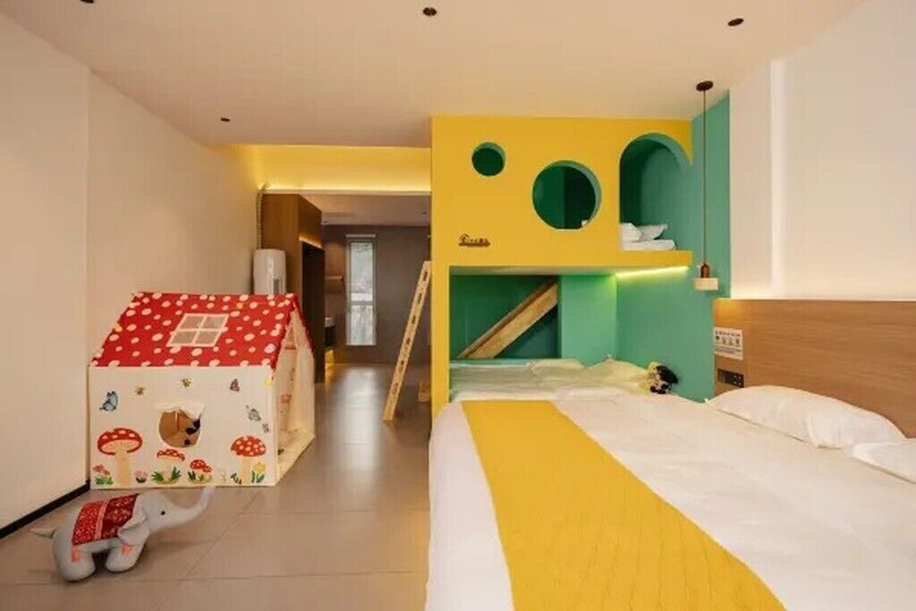Habitación de hotel con una cama, una casita de juegos y una escalera.