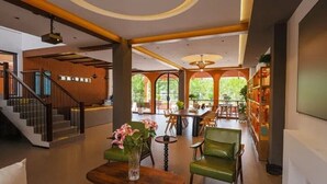 Un vestíbul ampli amb una escala, una recepció i una zona de seients amb un vas de flors.