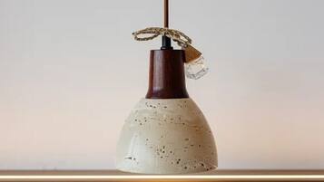 A pendant light with a textured ceramic shade and a wooden base.