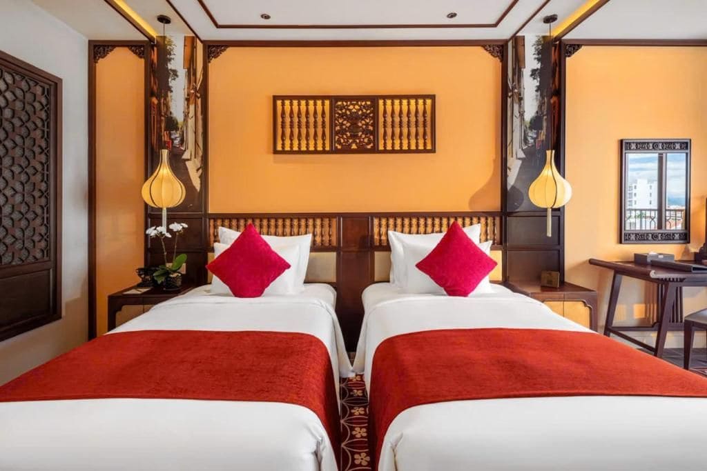 Ein Hotelzimmer mit zwei Betten, einer Zierwand und einem Schreibtisch mit Stuhl.