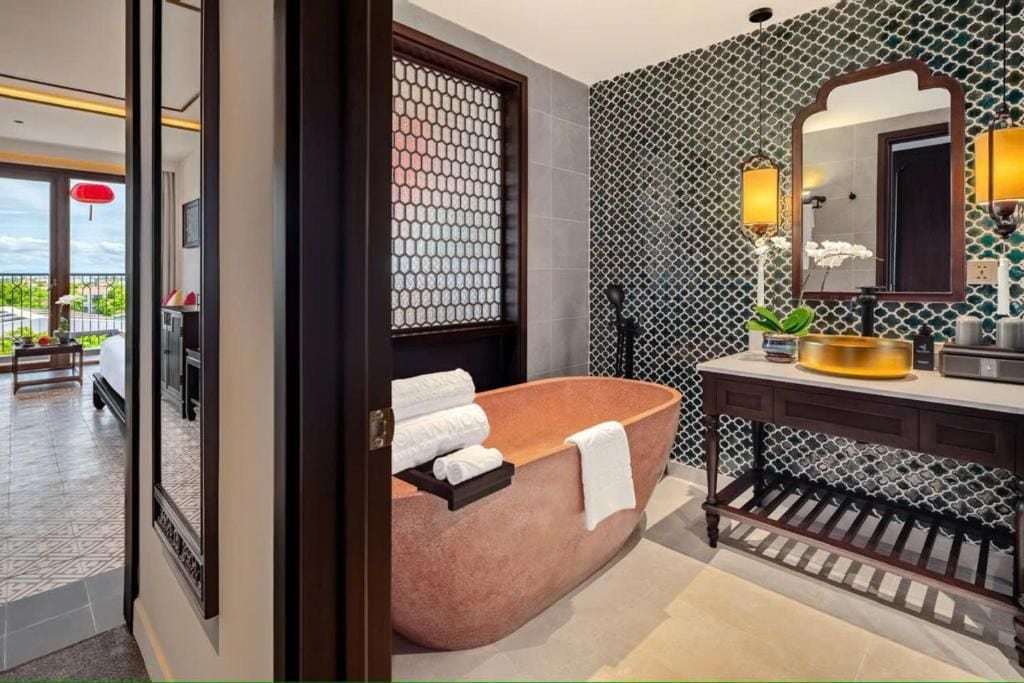 A modern bathroom with a freestanding bathtub, a vanity with a mirror, and a patterned wall.